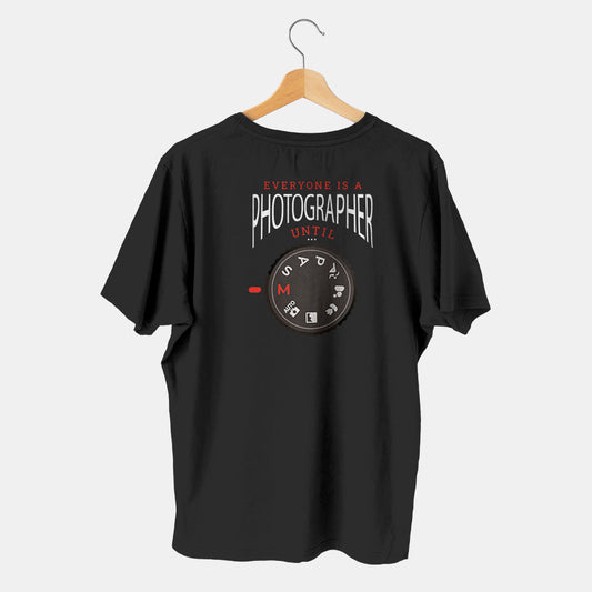 camistea negra con camara de fotos en modo manual con fondo blanco evryone is a photographer